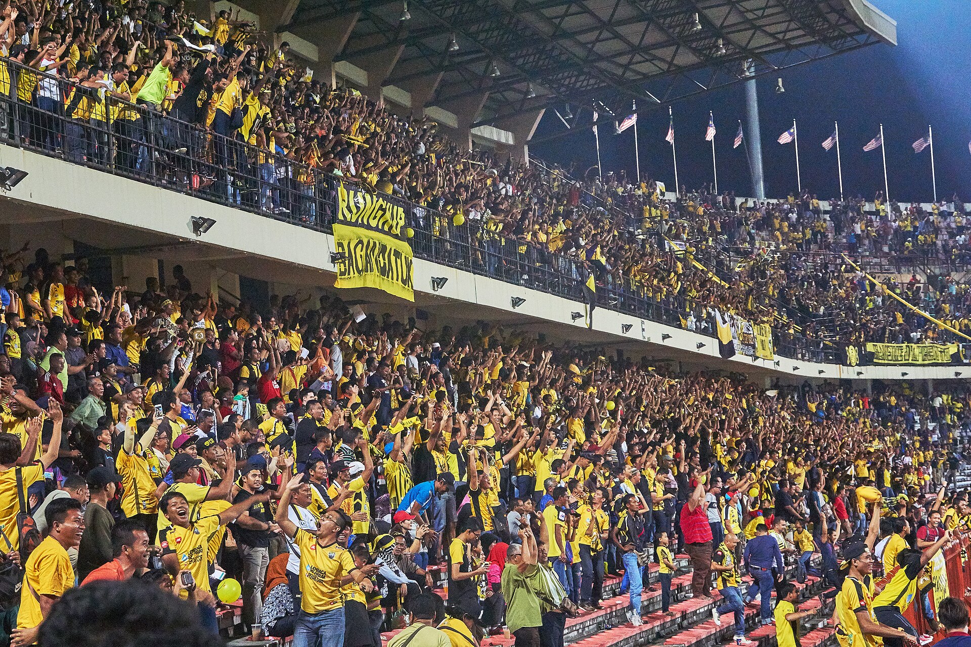 Football supporters behind a large stadium banner